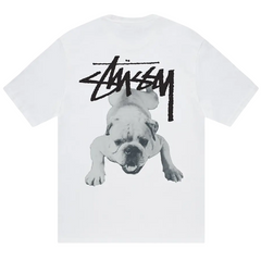 Stussy Stock Dog Tee White T-shirt med frontvisning, der viser den ikoniske Stüssy-logografik med en hund printet på brystet i hvidt stof.
